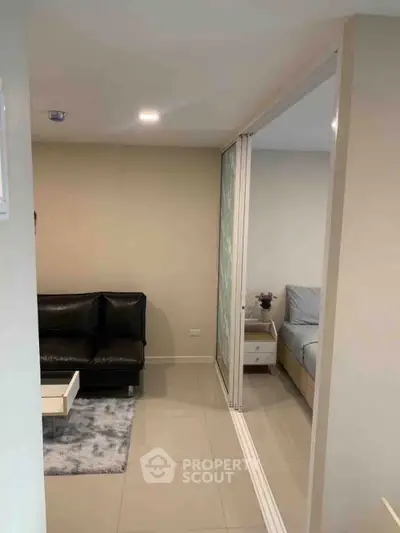 Modern apartment interior with sliding glass doors separating living room and bedroom.