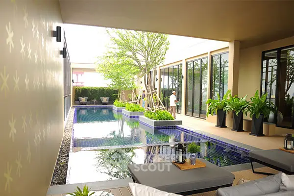 Luxurious modern poolside area with lush greenery and stylish decor.