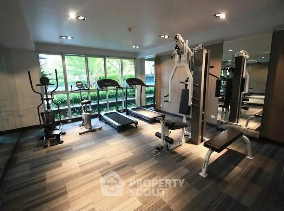 Modern gym with state-of-the-art equipment and large windows in a residential building.