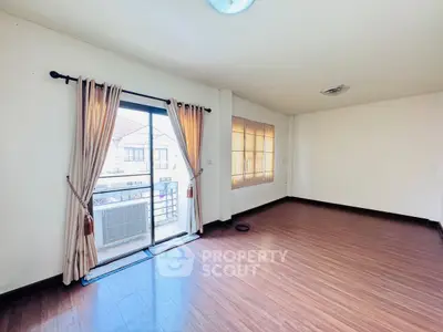 Spacious empty room with wooden flooring and large windows for natural light.