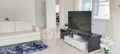 Spacious living room with modern decor and large TV in a bright apartment.
