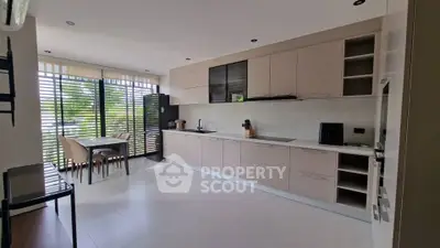 Spacious modern kitchen with sleek cabinetry and dining area, featuring large windows for natural light.
