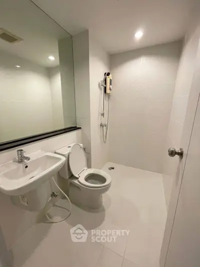 Modern minimalist bathroom with sleek fixtures and large mirror in a contemporary apartment.