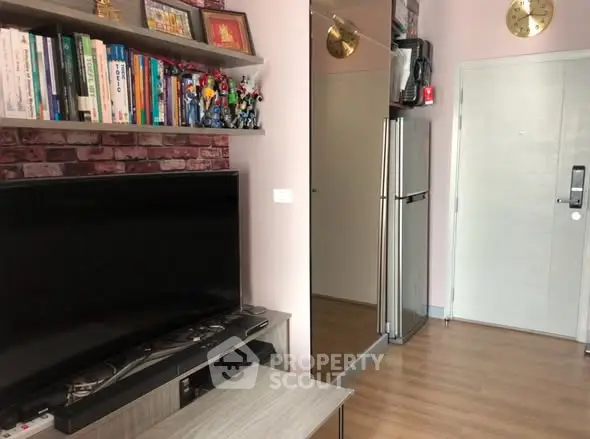 Modern living room with TV, bookshelf, and sleek refrigerator in a cozy apartment setting.