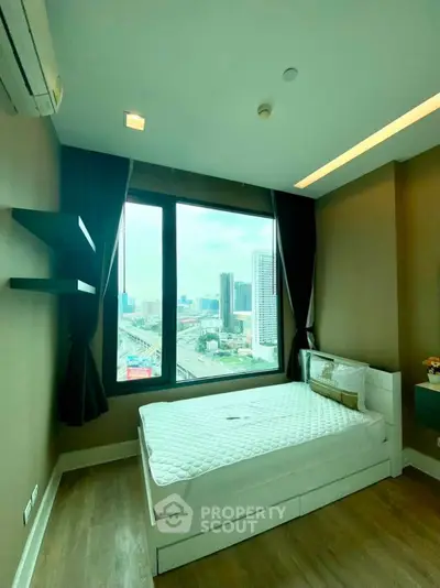 Modern bedroom with city view, featuring a comfortable bed and large window in a high-rise apartment.