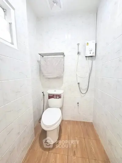 Modern bathroom with shower and toilet in bright white tiles.