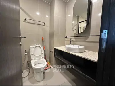 Modern bathroom with sleek fixtures and contemporary design, featuring a round mirror and stylish sink.