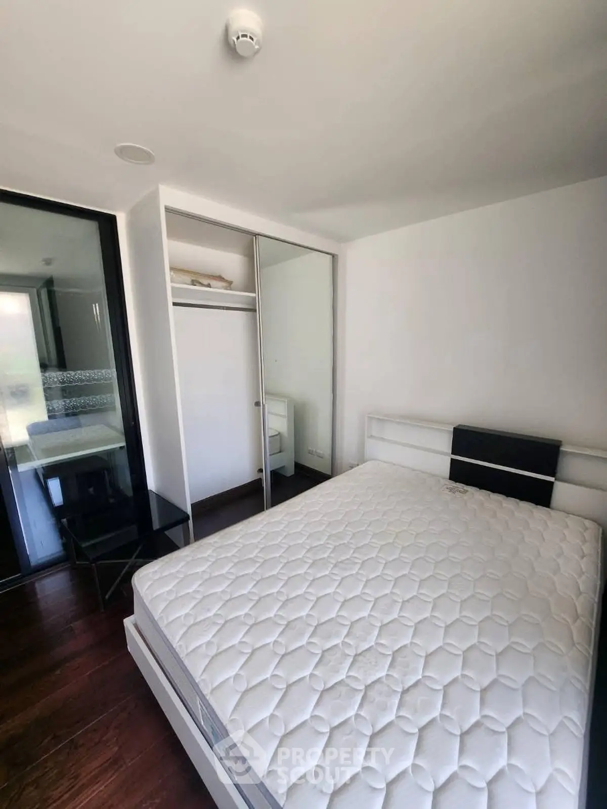 Modern bedroom with large bed and mirrored closet in a bright apartment.