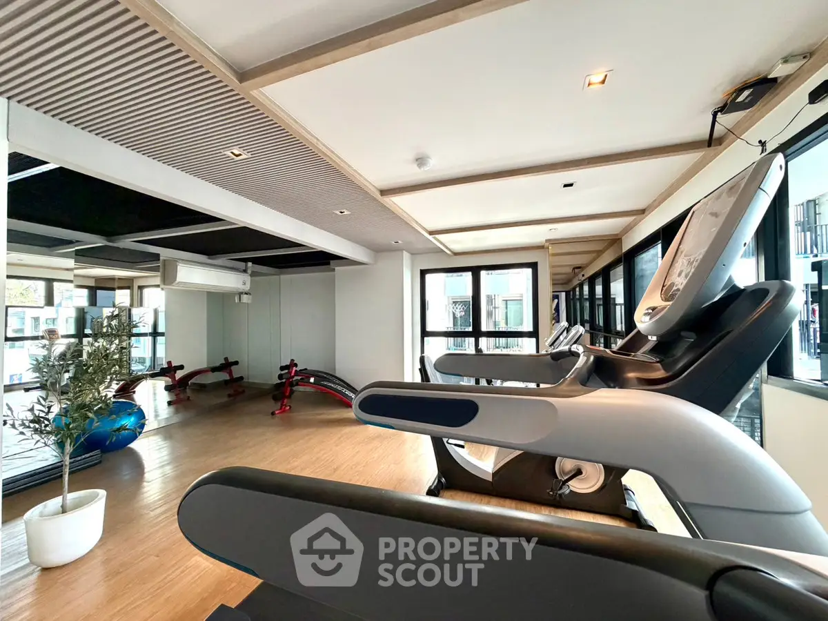 Modern gym with state-of-the-art equipment and large windows for natural light.