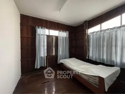 Cozy bedroom with wooden walls and natural light from large windows.