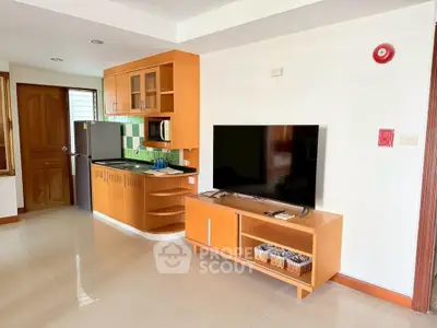 Modern living room with sleek kitchen and entertainment center, perfect for cozy urban living.