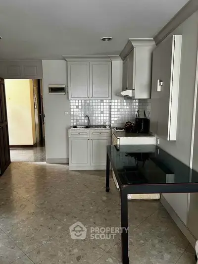 Modern kitchen with sleek cabinetry and tiled backsplash in a cozy apartment setting.