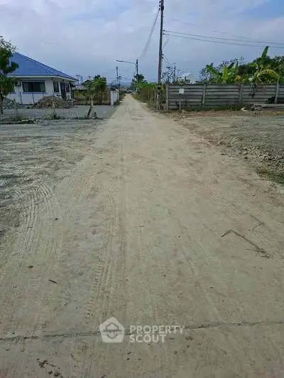 Expansive view of a developing residential area with a dirt road and new construction.