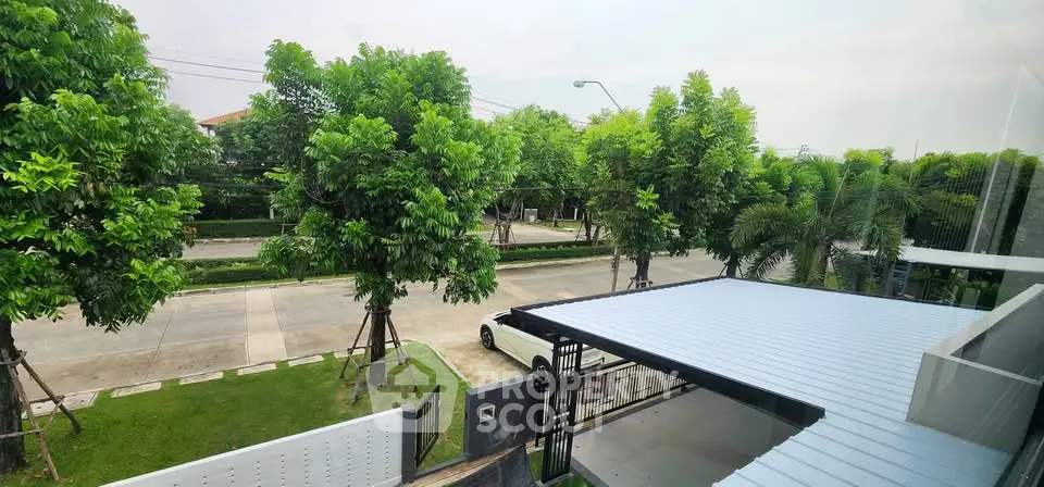 Charming suburban street view from modern home balcony with lush greenery.