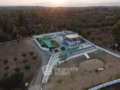 Stunning aerial view of a modern luxury villa with pool and expansive landscape at sunset.