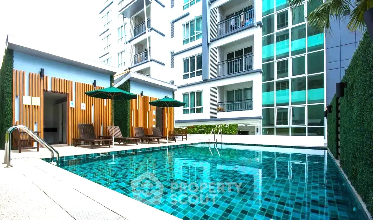 Modern apartment complex with a luxurious outdoor pool and stylish sun loungers.