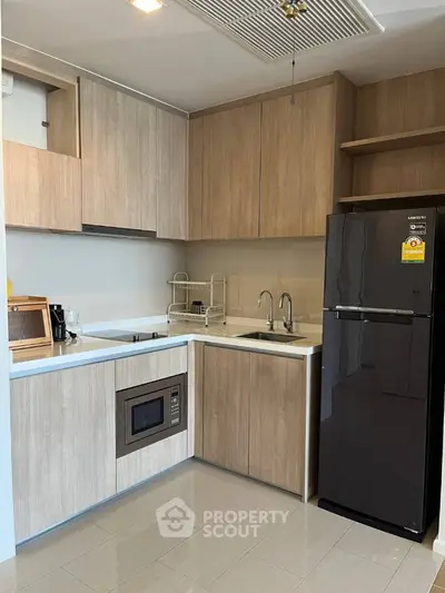 Modern kitchen with sleek cabinetry, built-in microwave, and spacious fridge in a stylish apartment.