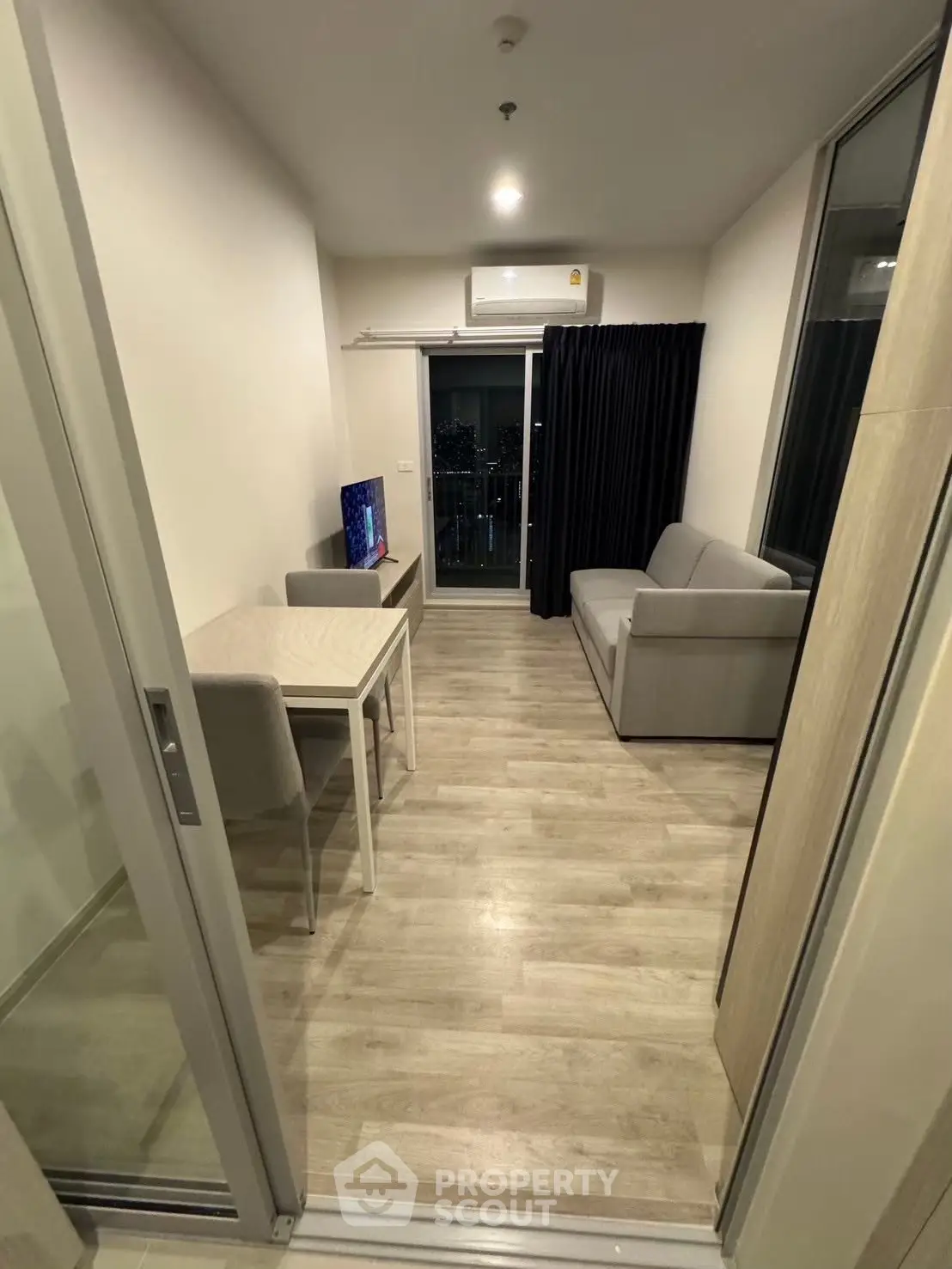 Modern living room with sleek furniture and balcony view, perfect for urban living.