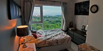 Cozy bedroom with stunning view of lush greenery and cityscape through large window.