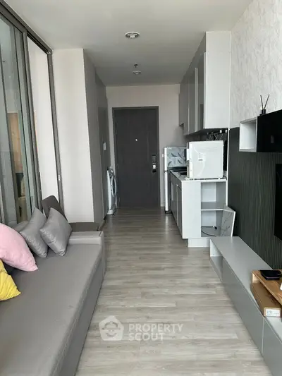 Modern living room with sleek kitchen and washing machine in open layout apartment.