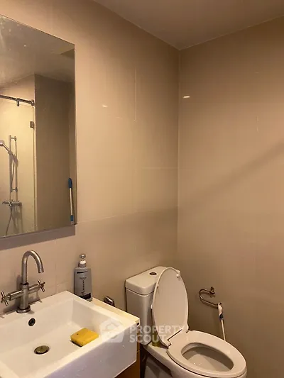 Modern bathroom with sleek fixtures and neutral tiles, featuring a toilet and sink.