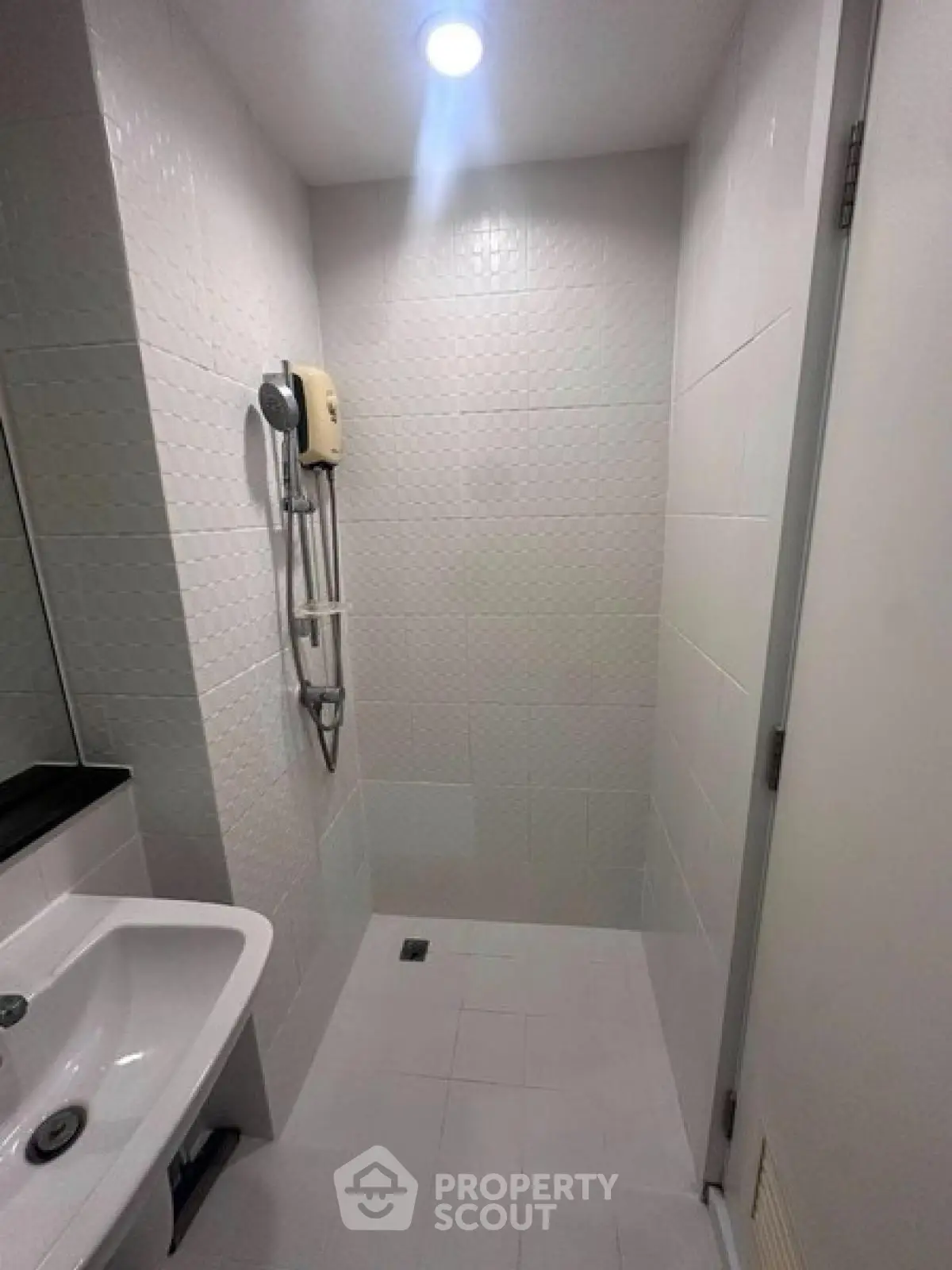 Compact modern bathroom with sleek white tiles and shower area.