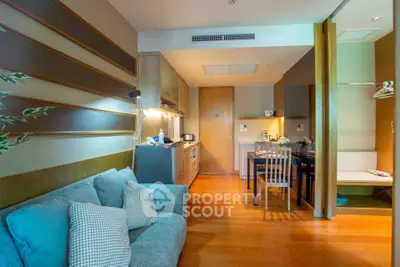 Modern studio apartment with cozy living area and compact kitchen, featuring wooden flooring and stylish decor.