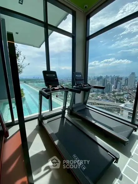 Modern gym with treadmills and stunning city view through large windows.