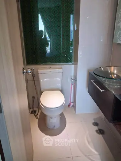 Modern bathroom with sleek fixtures and stylish glass sink in a compact layout.