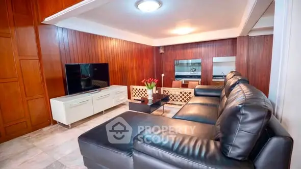 Luxurious living room with leather sofa and modern TV setup in elegant wood-paneled interior.