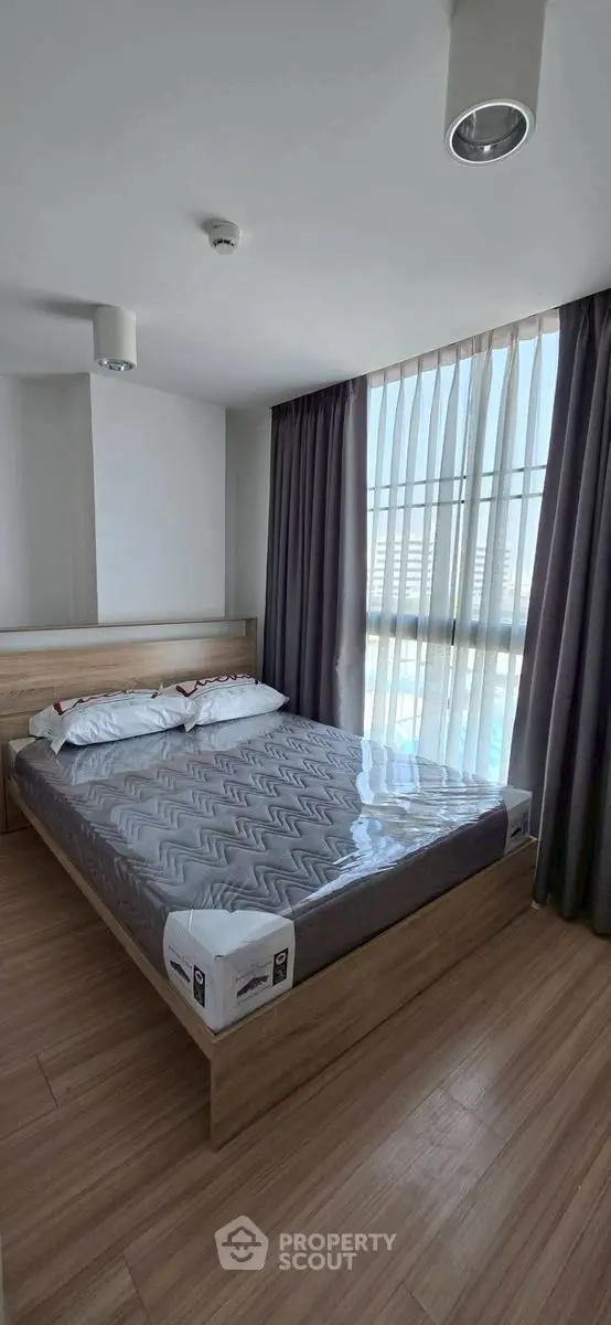 Modern bedroom with large window and stylish wooden flooring.