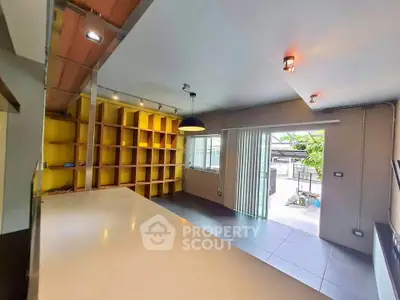 Modern open-plan living area with bright yellow shelving and large windows for natural light.