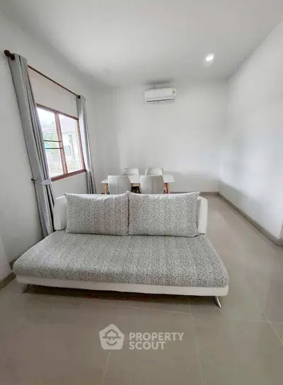 Modern living room with cozy sofa and dining area, featuring neutral tones and natural light.