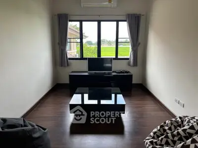 Modern living room with large window and sleek furniture, offering a serene view of greenery.