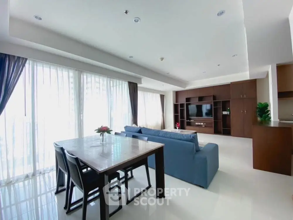 Spacious modern living room with large windows and elegant dining area