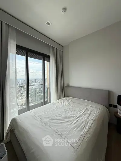 Modern bedroom with city view through large windows, featuring a cozy bed and minimalist decor.