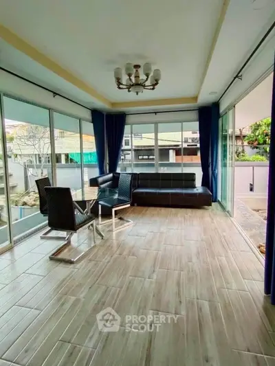 Spacious sunlit room with modern furniture and large windows offering a serene view.