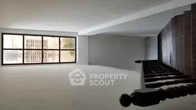 Spacious interior with large window and staircase, ideal for creative renovation.