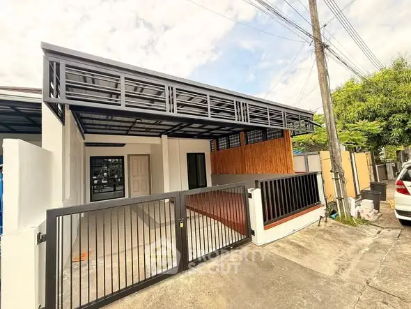 Modern single-story house with gated entrance and carport in suburban neighborhood.