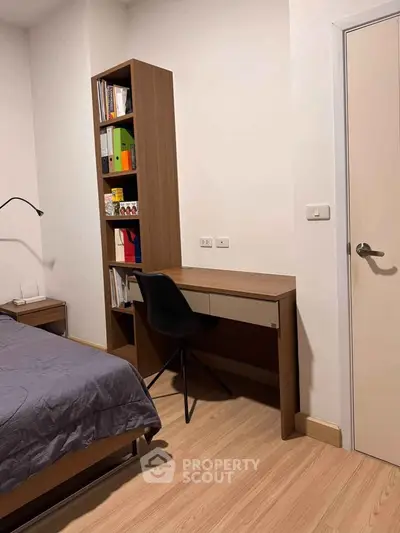 Modern bedroom with study area featuring a sleek desk and bookshelf, perfect for work-from-home setup.
