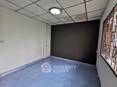 Spacious empty room with blue tiled floor and large window, ideal for customization.