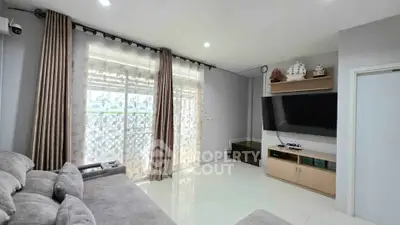 Modern living room with large TV and cozy sofa, featuring elegant curtains and sleek design.
