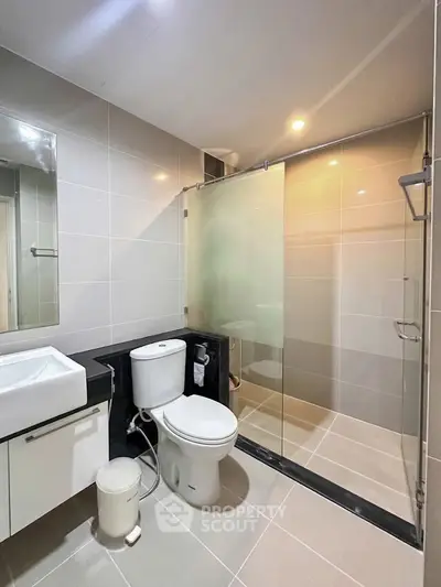 Modern bathroom with glass shower and sleek fixtures in contemporary apartment.