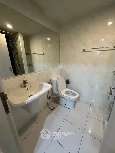 Modern bathroom with sleek white tiles and large mirror