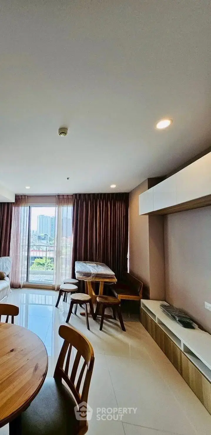 Spacious living room with modern furniture and large windows offering city views.