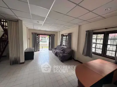 Spacious living room with tiled floor and large windows offering natural light.