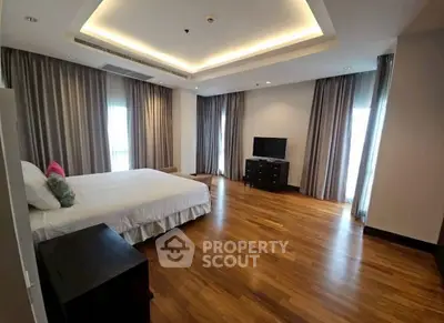Spacious bedroom with wooden flooring and modern decor in luxury apartment.