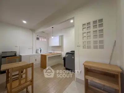Modern kitchen with open layout and wooden furniture, featuring sleek appliances and ample lighting.