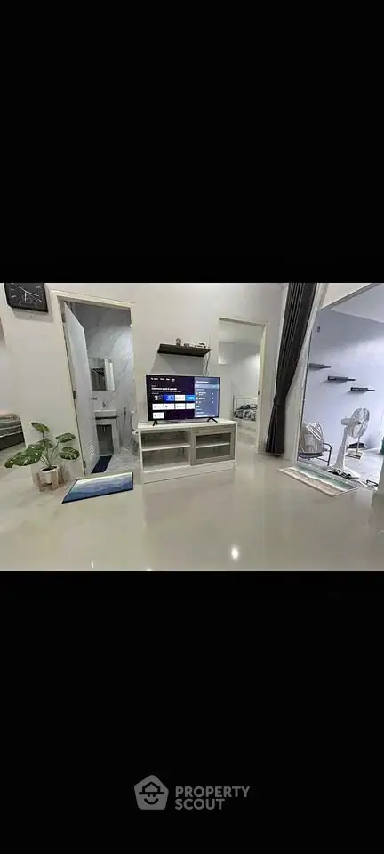 Modern living room with sleek TV setup and open layout, featuring glossy floors and stylish decor.