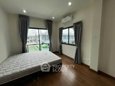 Spacious bedroom with large windows and hardwood floors in modern home